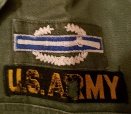 A Combat Infantryman's Badge sewn above a U.S. Army tape on a fatigue shirt