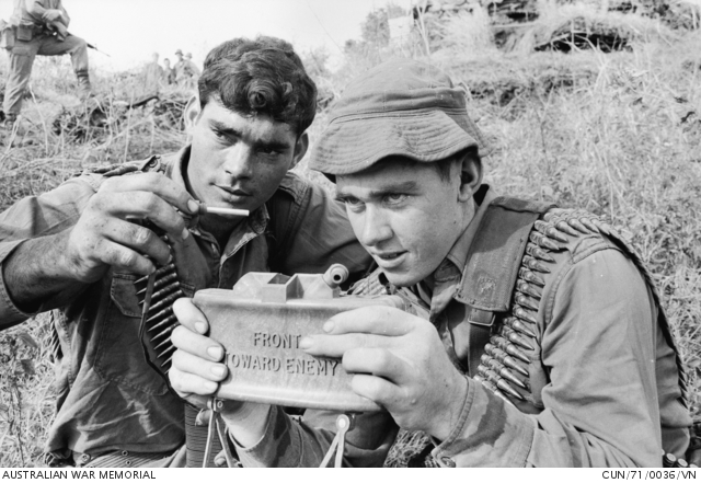 Two soldiers aim a Claymore mine, its face stamped FRONT TOWARD ENEMY, during a patrol
