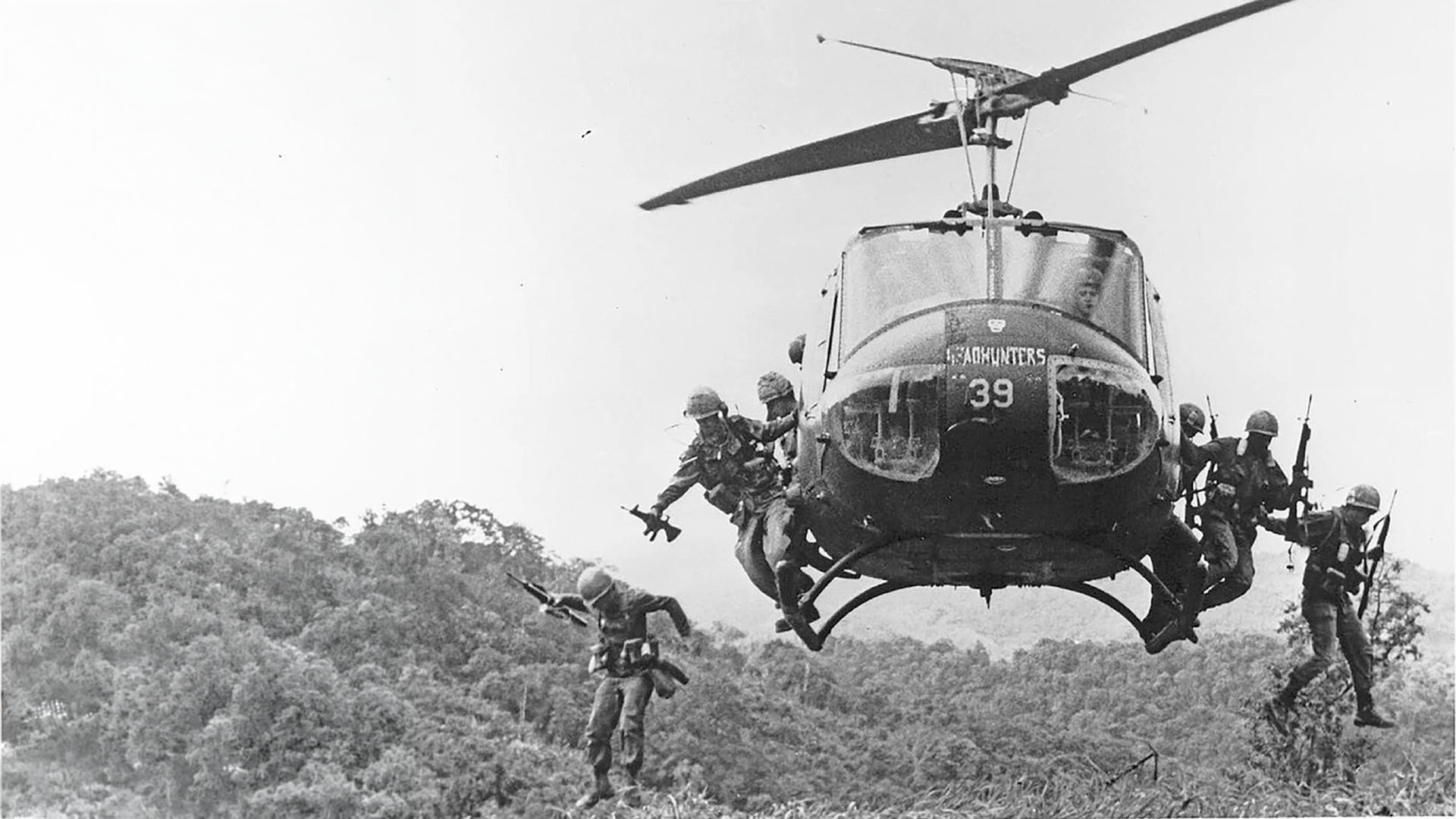 Soldiers leaping from a hovering Huey helicopter into elephant grass, Vietnam