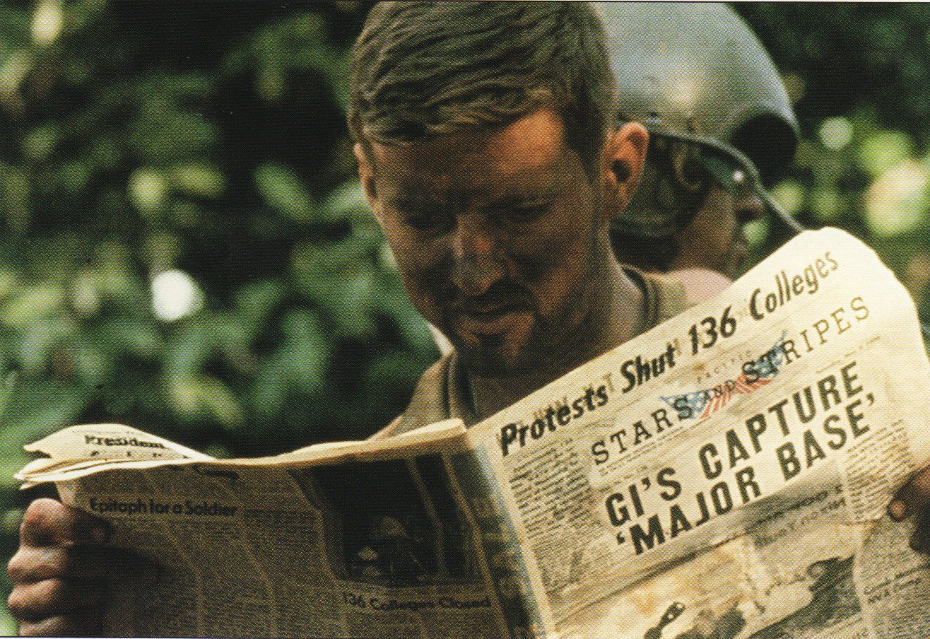 A soldier reads Stars and Stripes during the Cambodian campaign, the front page headlined GI'S CAPTURE 'MAJOR BASE'